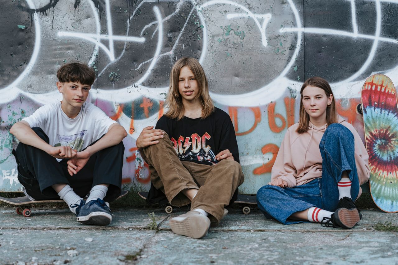 Eine Gruppe Jugendlicher sitz auf ihren Skateboards an einer Wand